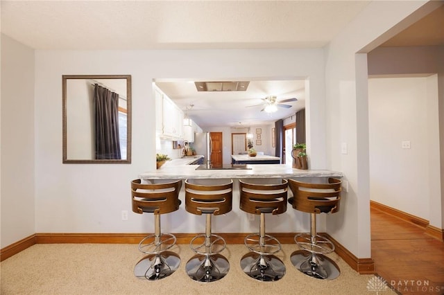 bar featuring stainless steel fridge, white cabinetry, and ceiling fan