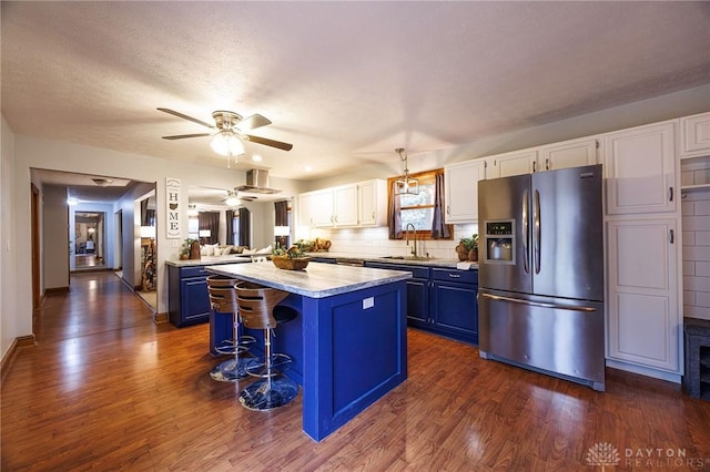 kitchen featuring stainless steel refrigerator with ice dispenser, a kitchen island, sink, blue cabinetry, and white cabinetry