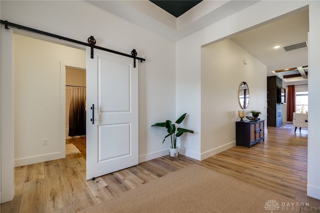 hallway with a barn door and light wood-type flooring