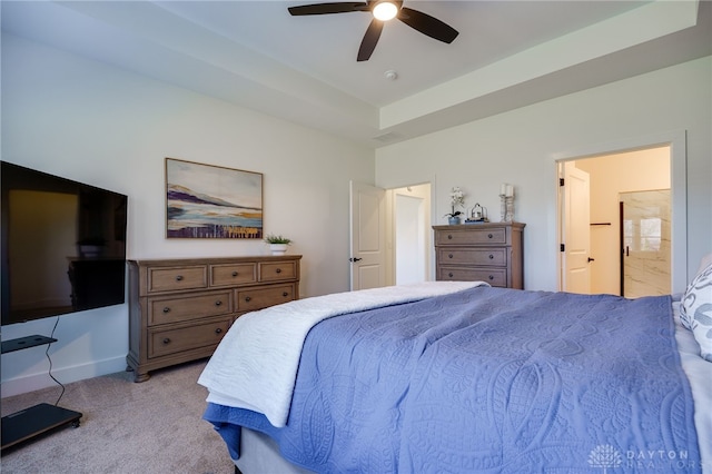 carpeted bedroom with ceiling fan, a raised ceiling, and ensuite bath