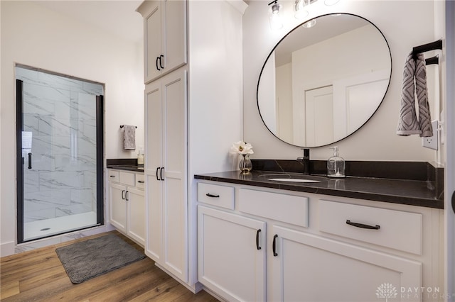 bathroom with walk in shower, vanity, and hardwood / wood-style flooring