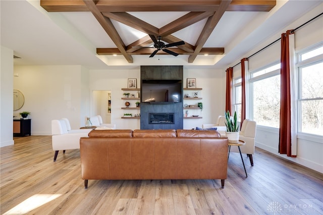 living room with coffered ceiling, a large fireplace, ceiling fan, beam ceiling, and light hardwood / wood-style flooring