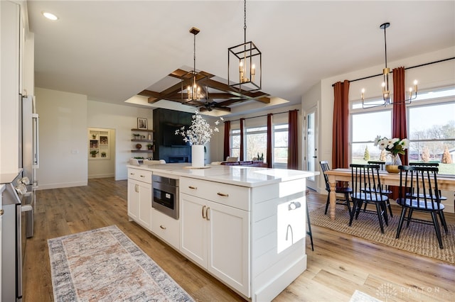 kitchen featuring light hardwood / wood-style flooring, white cabinetry, hanging light fixtures, and a kitchen island