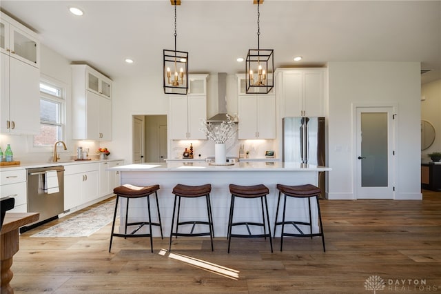 kitchen with a kitchen island with sink, dark wood-type flooring, wall chimney exhaust hood, white cabinetry, and stainless steel appliances