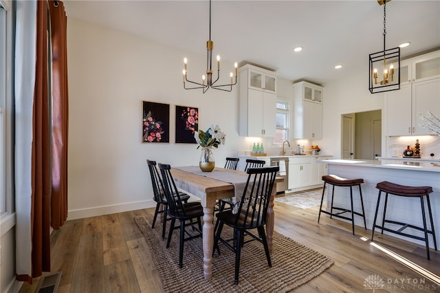 dining space with light hardwood / wood-style flooring and an inviting chandelier