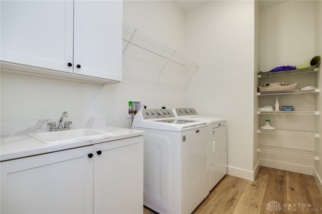 clothes washing area featuring light hardwood / wood-style floors, cabinets, separate washer and dryer, and sink