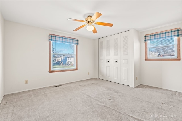 unfurnished bedroom with light carpet, a closet, and ceiling fan