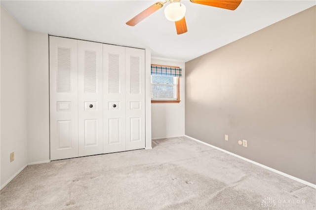 unfurnished bedroom with ceiling fan, light colored carpet, and a closet