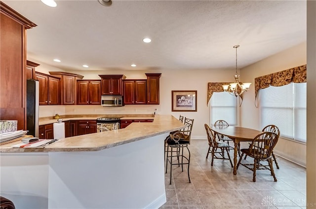 kitchen featuring a kitchen bar, kitchen peninsula, appliances with stainless steel finishes, hanging light fixtures, and a chandelier