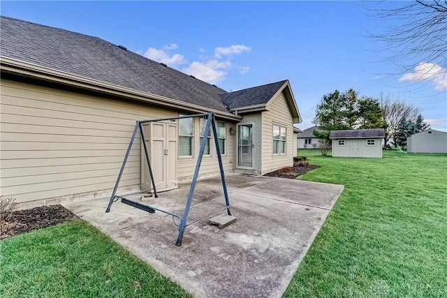 rear view of property featuring a storage unit, a lawn, and a patio