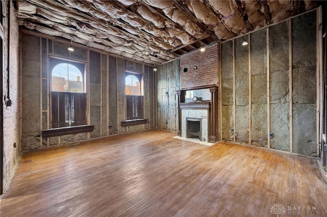 unfurnished living room with hardwood / wood-style floors and a brick fireplace