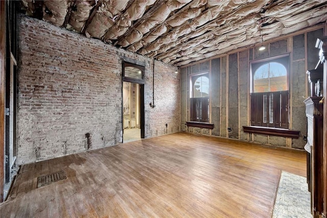 unfurnished room featuring hardwood / wood-style floors and brick wall