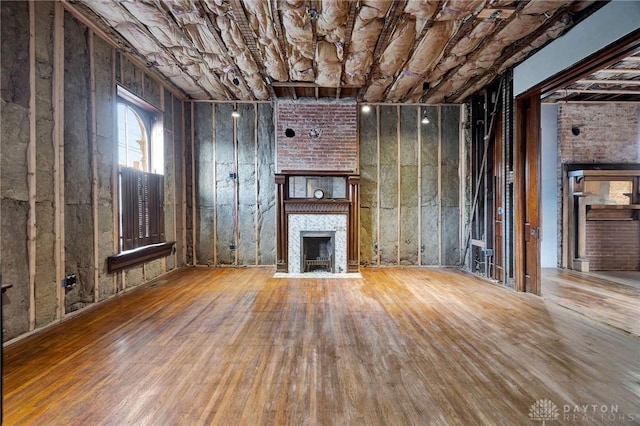 unfurnished living room featuring wood-type flooring and a brick fireplace