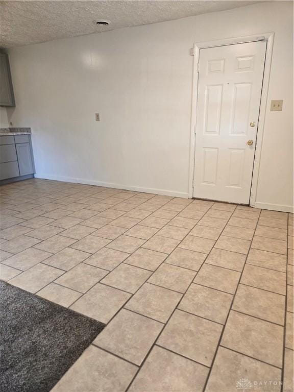 unfurnished room with light tile patterned floors and a textured ceiling