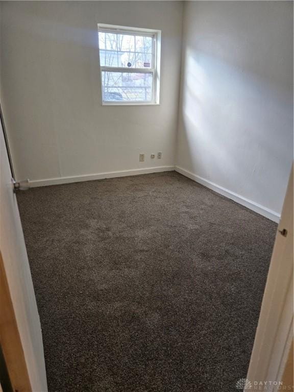 unfurnished room featuring dark carpet