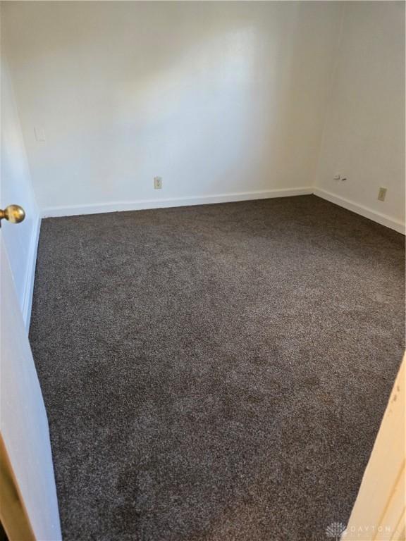 spare room featuring dark carpet