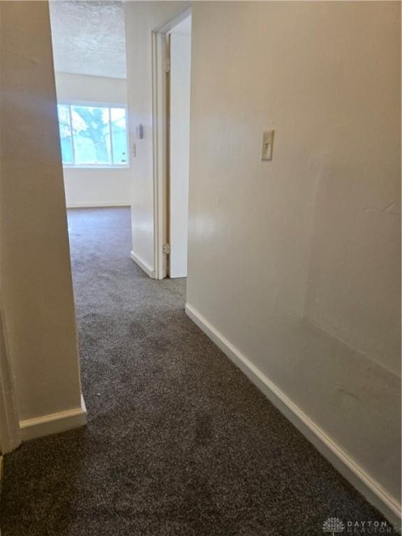 hallway featuring dark colored carpet