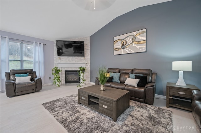 living room with ceiling fan, a fireplace, and vaulted ceiling