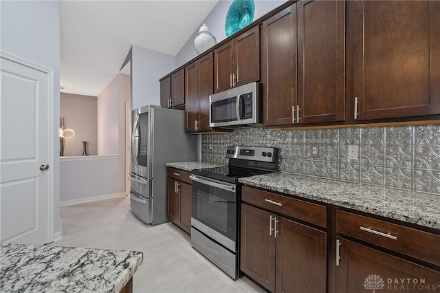 kitchen with light stone countertops, appliances with stainless steel finishes, tasteful backsplash, dark brown cabinetry, and vaulted ceiling