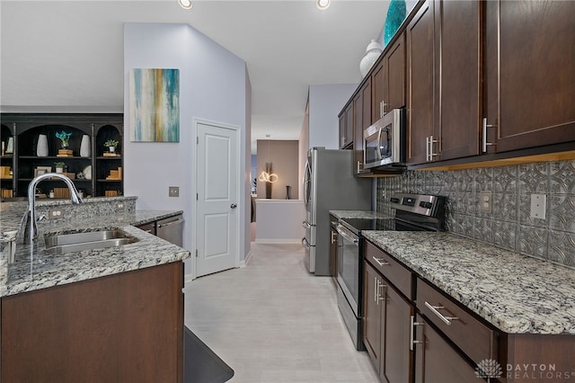 kitchen featuring light stone countertops, appliances with stainless steel finishes, dark brown cabinets, and sink