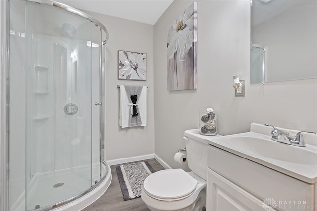 bathroom featuring hardwood / wood-style flooring, vanity, a shower with shower door, and toilet