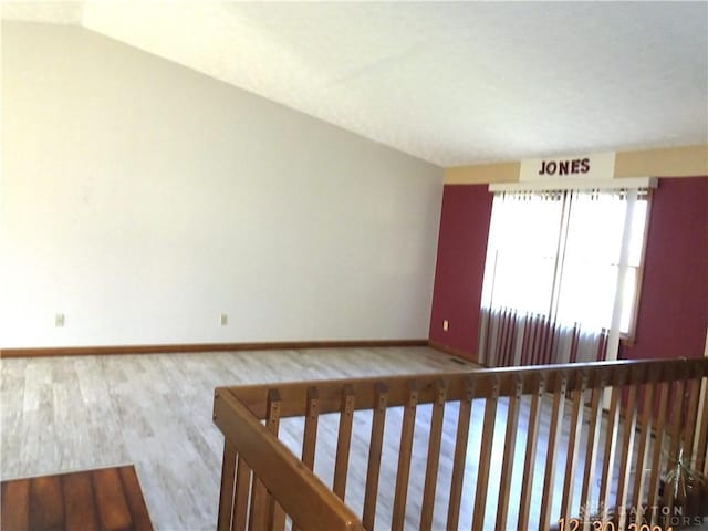 spare room with light hardwood / wood-style floors and vaulted ceiling