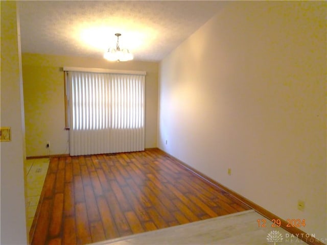 empty room with a chandelier and hardwood / wood-style flooring