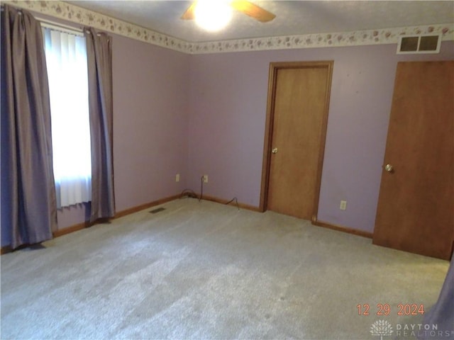 carpeted empty room with ceiling fan and a healthy amount of sunlight