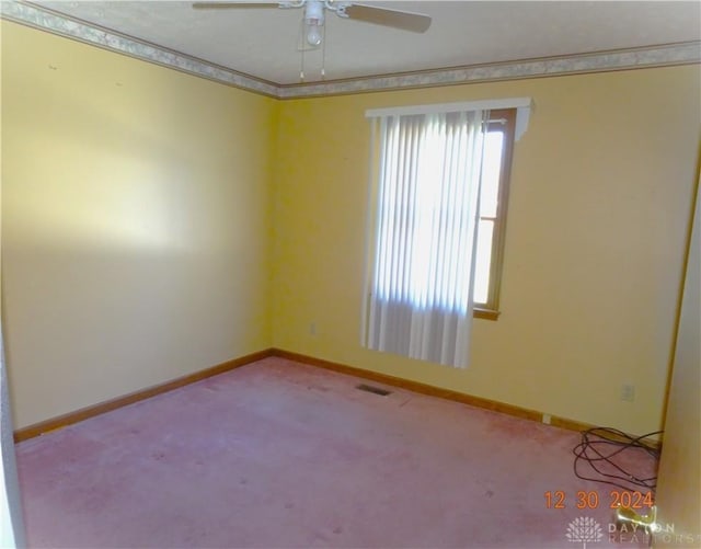 carpeted spare room featuring plenty of natural light, ceiling fan, and ornamental molding