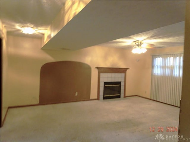 unfurnished living room with a tile fireplace, ceiling fan, and light carpet