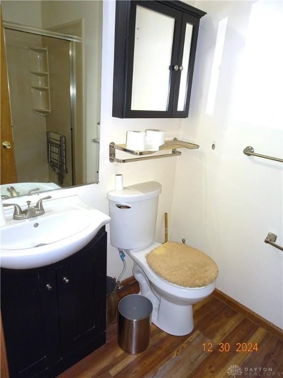 bathroom featuring toilet, a shower with door, vanity, and hardwood / wood-style flooring