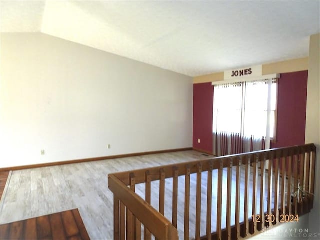 spare room featuring vaulted ceiling and hardwood / wood-style flooring