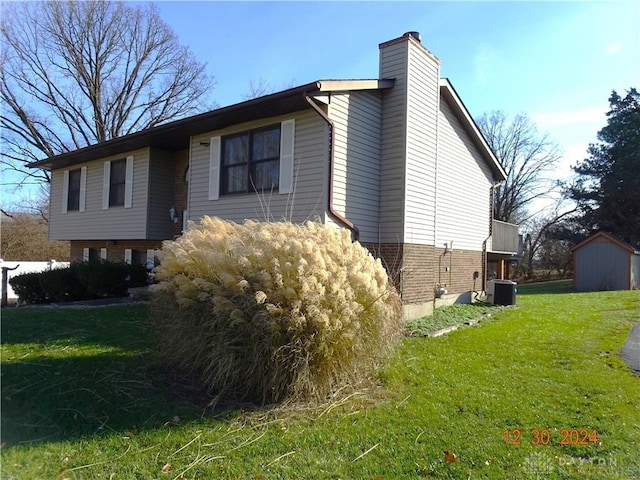 view of home's exterior featuring central air condition unit, a storage unit, and a lawn