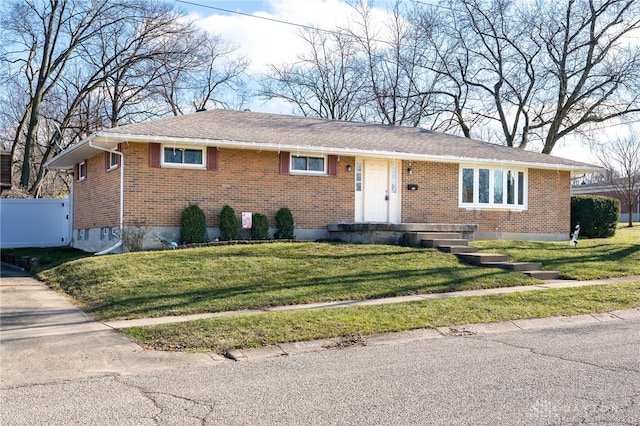 single story home featuring a front yard, brick siding, and fence