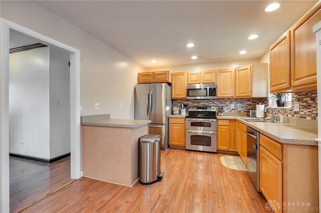 kitchen featuring light brown cabinets, a sink, light wood-style floors, light countertops, and appliances with stainless steel finishes