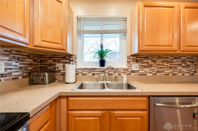 kitchen featuring light countertops, appliances with stainless steel finishes, a sink, and tasteful backsplash