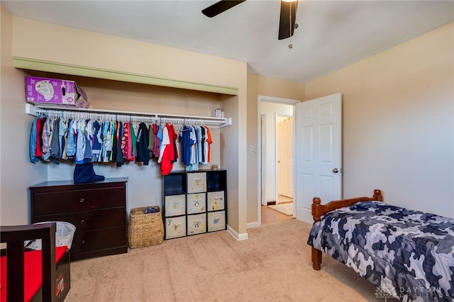 bedroom with light carpet, ceiling fan, a closet, and baseboards