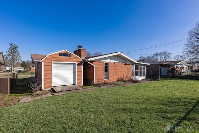 rear view of house with a garage, a yard, and an outbuilding