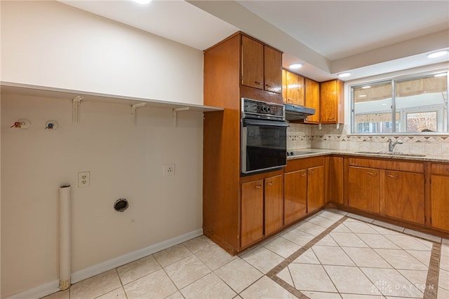 kitchen featuring tasteful backsplash, sink, light tile patterned floors, light stone counters, and black appliances