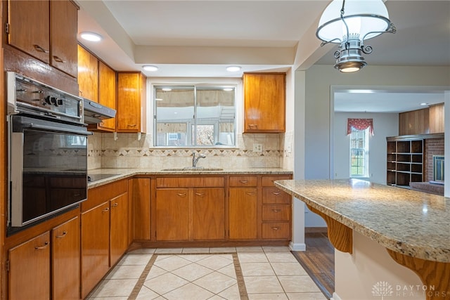 kitchen with pendant lighting, black appliances, sink, light tile patterned floors, and tasteful backsplash