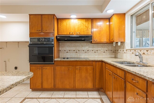 kitchen featuring light stone countertops, sink, backsplash, light tile patterned floors, and black appliances