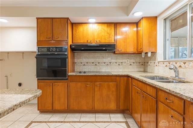 kitchen with sink, light tile patterned floors, light stone countertops, decorative backsplash, and black appliances