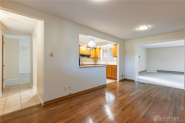 unfurnished living room with a baseboard heating unit and hardwood / wood-style floors