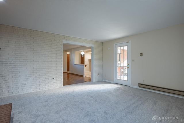 carpeted spare room with brick wall and baseboard heating