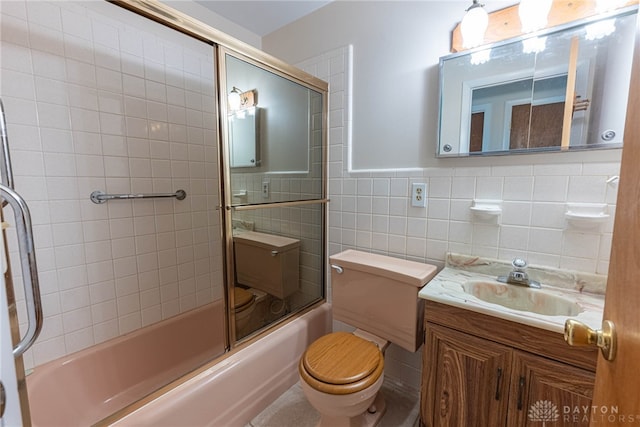 full bathroom with vanity, toilet, combined bath / shower with glass door, and tile walls