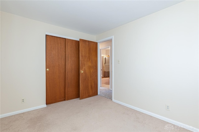 unfurnished bedroom with light carpet and a closet