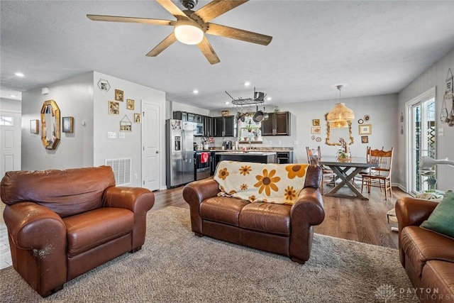 living room featuring hardwood / wood-style floors, ceiling fan, and a textured ceiling