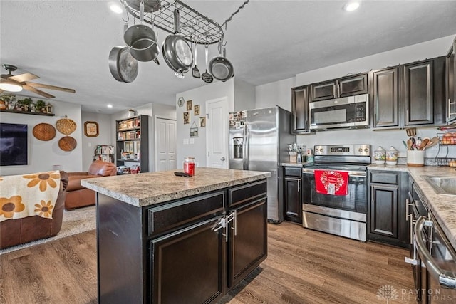 kitchen featuring hardwood / wood-style floors, stainless steel appliances, a kitchen island, and ceiling fan