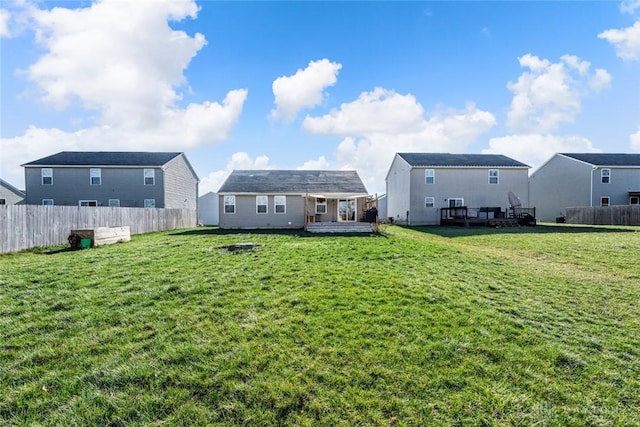 back of property with a deck, a yard, and an outbuilding