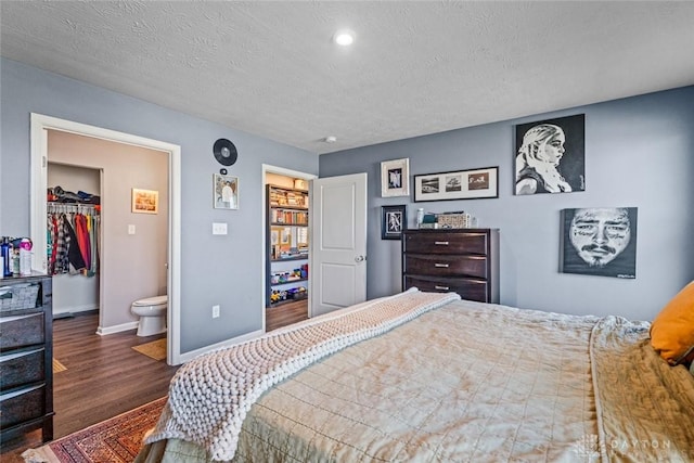 bedroom with ensuite bathroom, a closet, a textured ceiling, and dark wood-type flooring